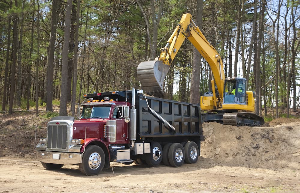 An excavator putting dirt into a dump truck